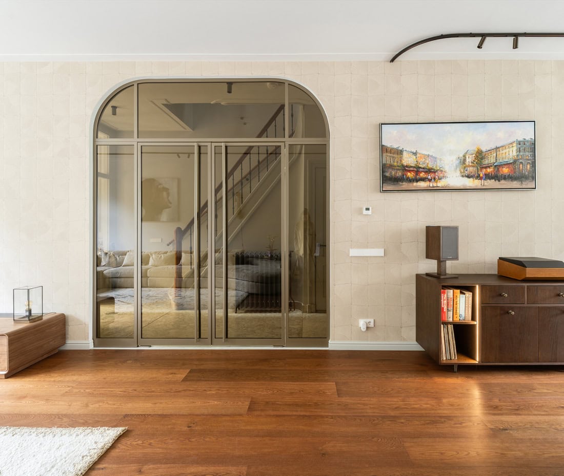 Stalen trapdeur in modern interieur met houten vloer en kunstwerk.