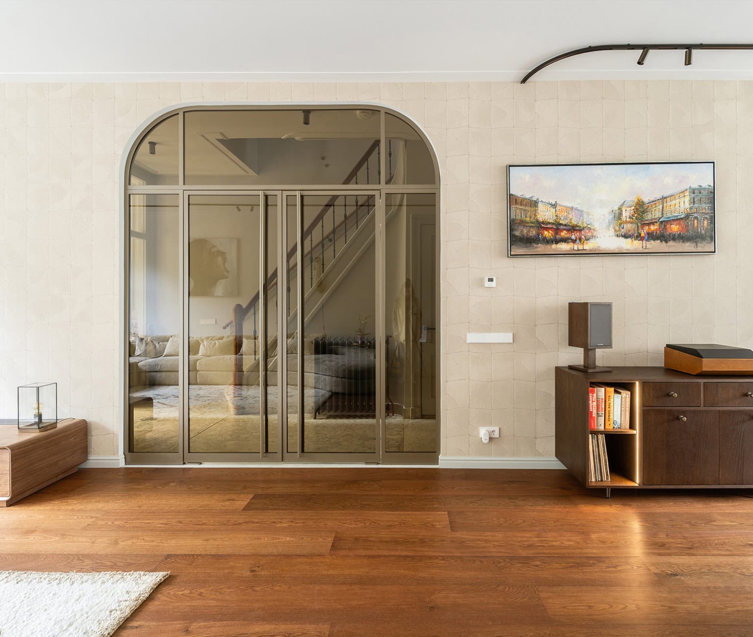 Stalen trapdeur in modern interieur met houten vloer en kunstwerk.