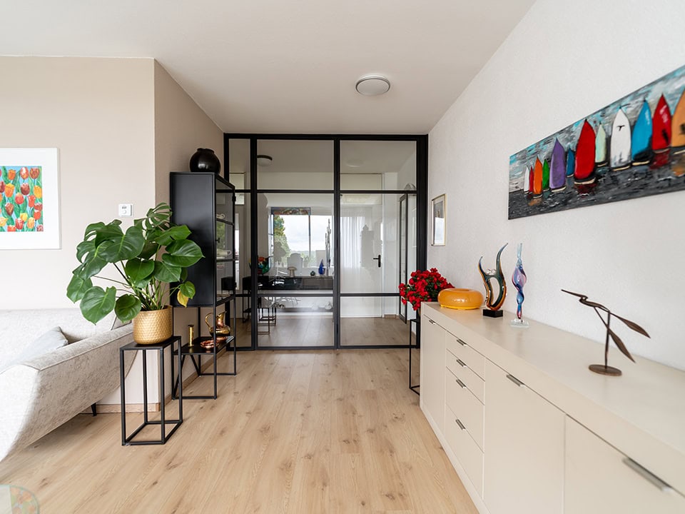 Moderne woonkamer met vouwdeuren en decoratieve accessoires.