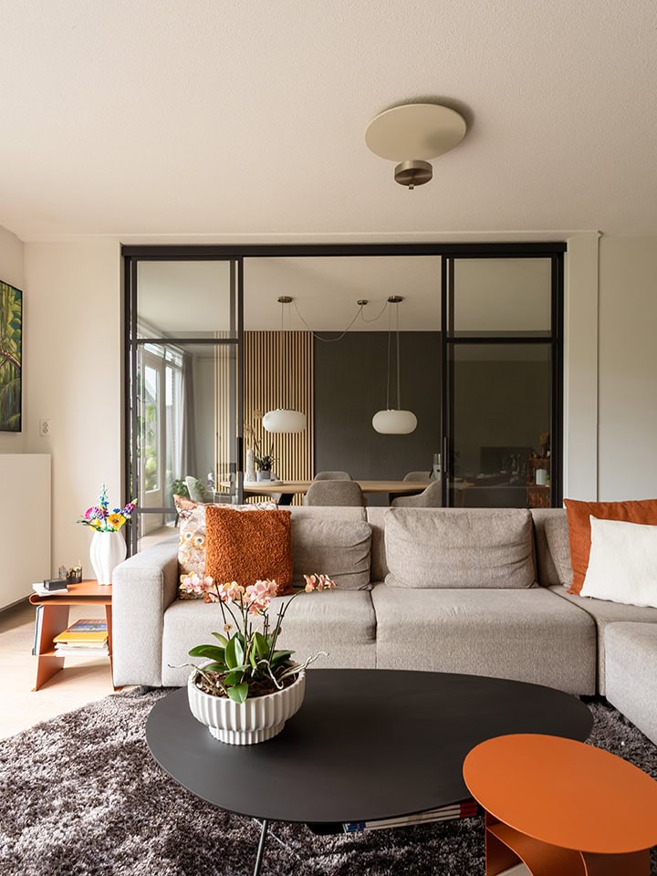 Moderne woonkamer met glazen schuifdeur en comfortabele zithoek.
