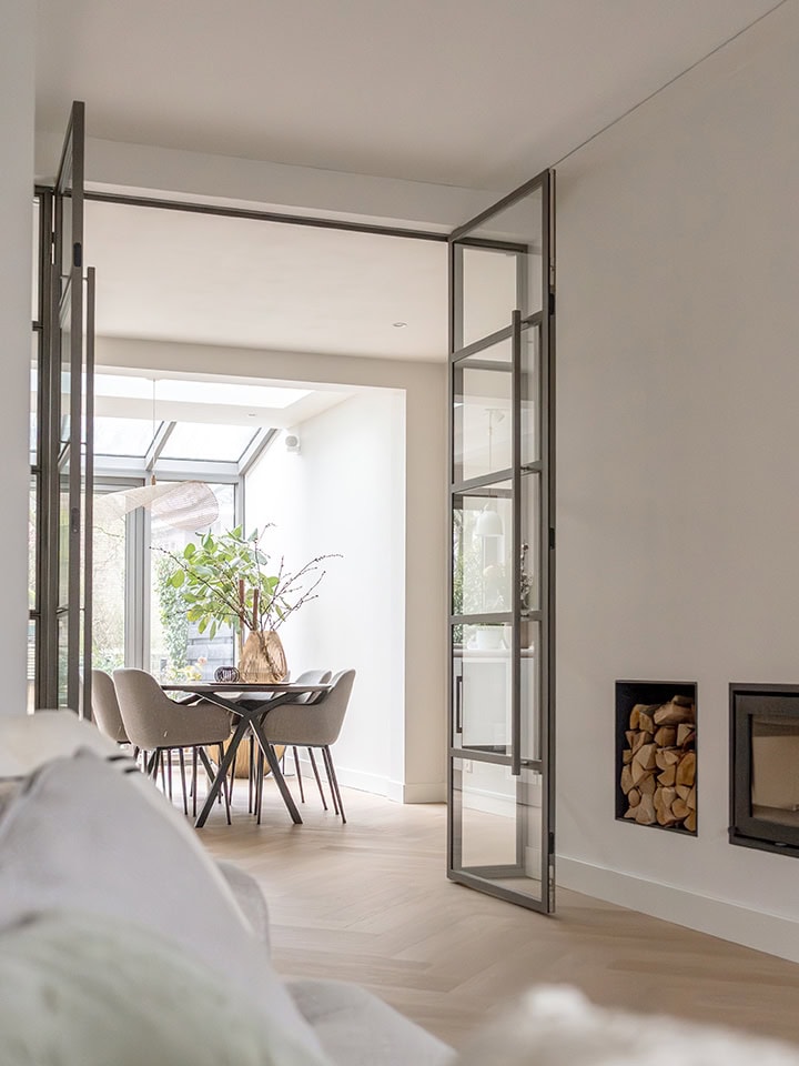 Moderne scharnierdeuren in een lichte woonkamer met uitzicht op tuin.