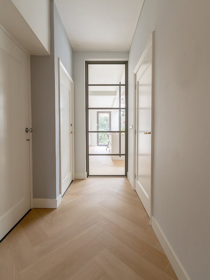 Moderne scharnierdeur in een lichte, minimalistische hal.