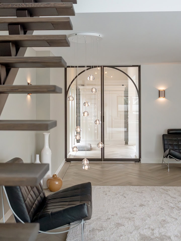 Moderne taatsdeur met glazen panelen en zwarte frame in eigentijdse woonkamer.