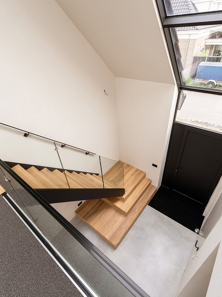 Stalen trap met glazen balustrade en eikenhouten treden.