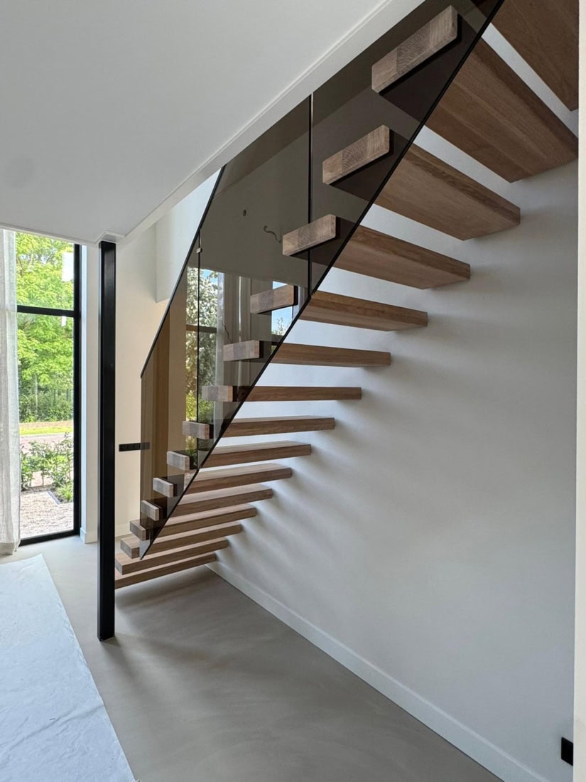 Moderne houten trap met glazen balustrade in een lichte woning.