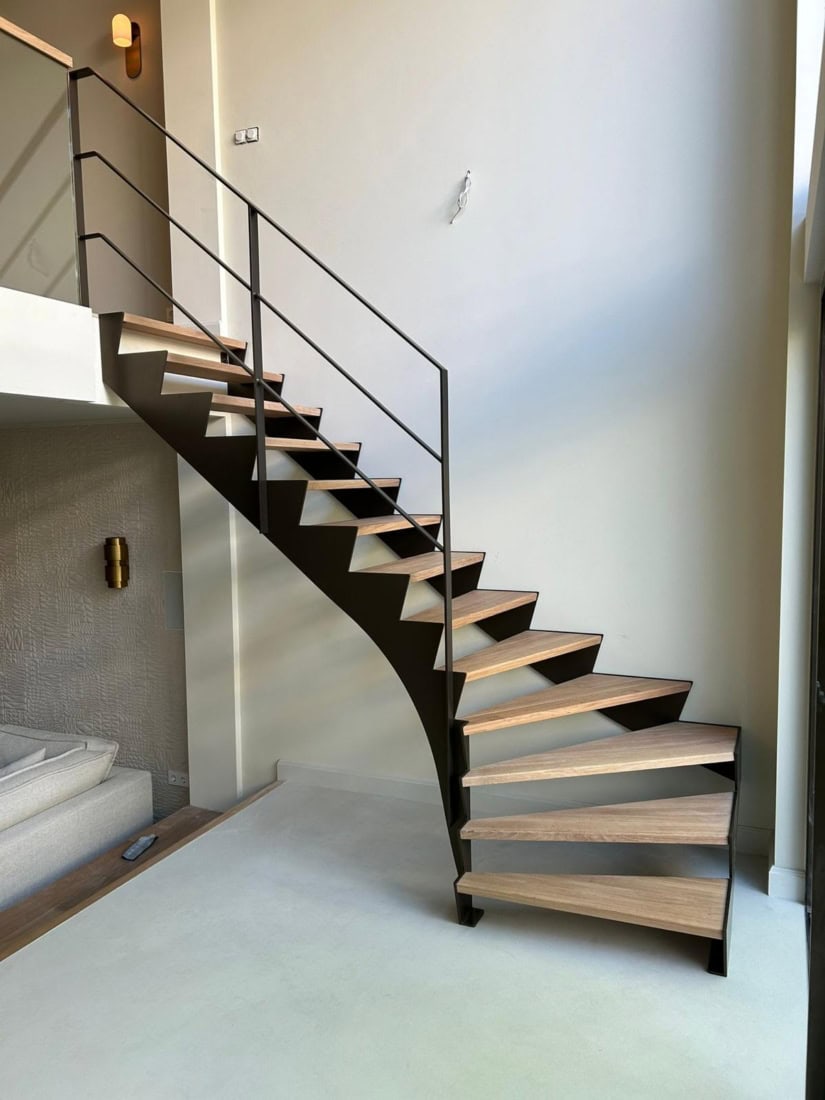 Moderne wenteltrap met houten treden en zwart metalen leuning in een interieur.