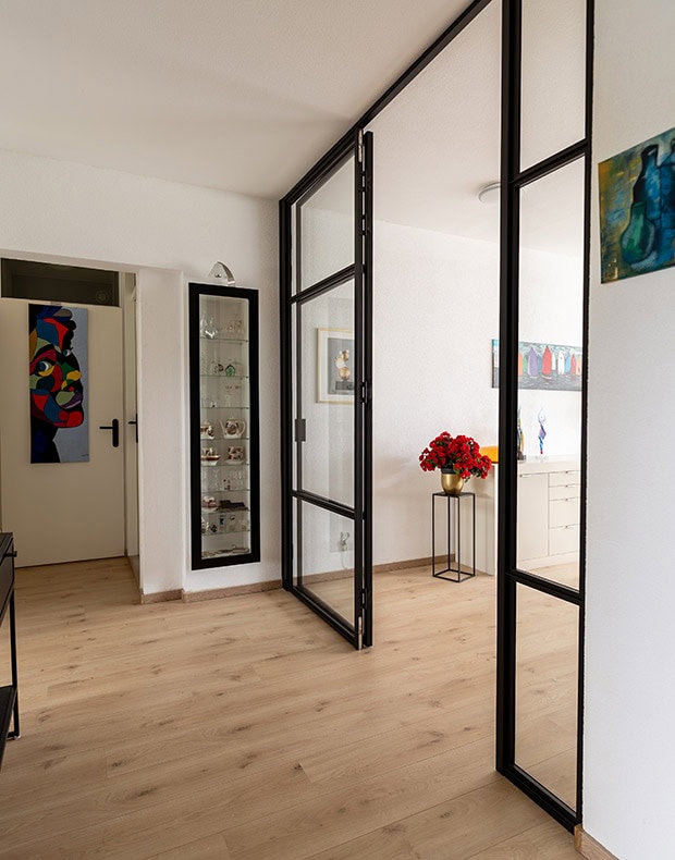 Moderne vouwdeuren met zwart metalen frame en glazen panelen in interieur.