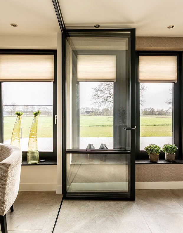 Moderne vouwdeur met zwart frame en grote ramen in woonkamer.