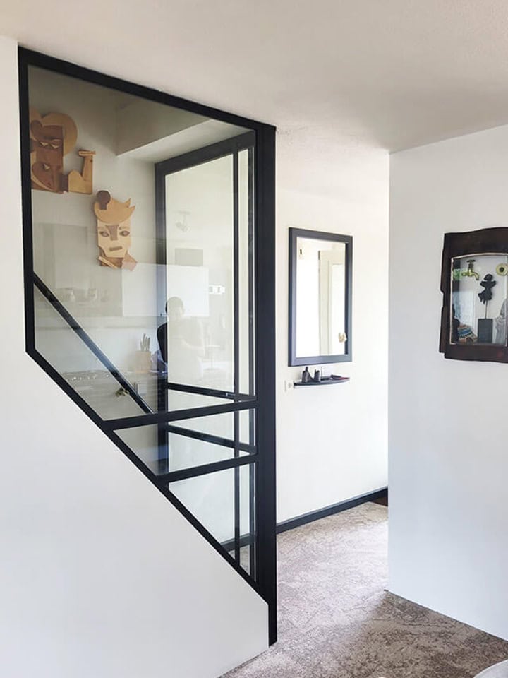 Moderne interieurafbeelding met zwart metalen scheidingswand en decoratieve kunst.